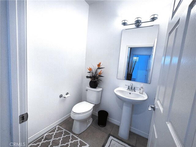 bathroom with toilet, a sink, tile patterned floors, and baseboards