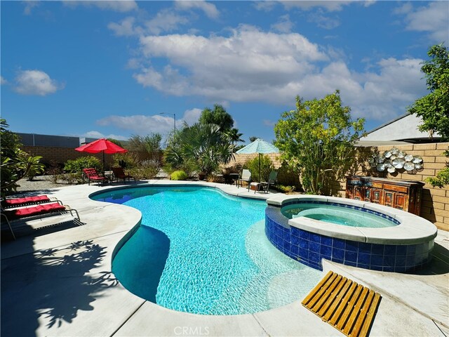 view of swimming pool with a patio area, fence private yard, and a pool with connected hot tub