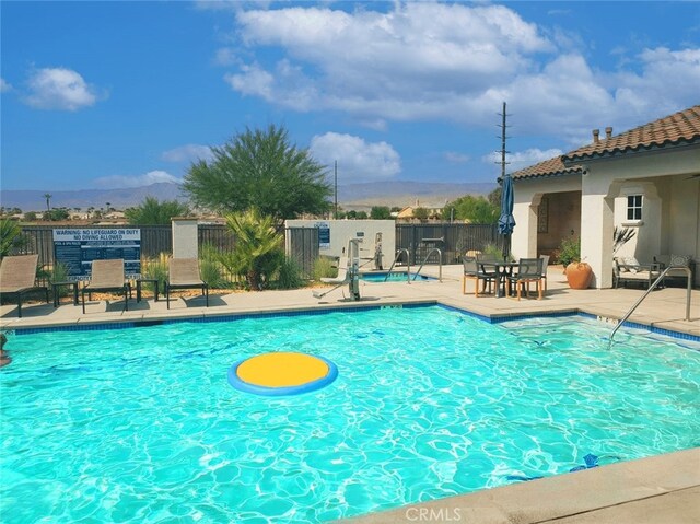 pool with a mountain view, a patio, and fence