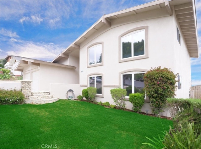 rear view of property featuring stucco siding and a lawn