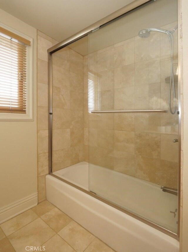 bathroom featuring tile patterned floors, combined bath / shower with glass door, and baseboards