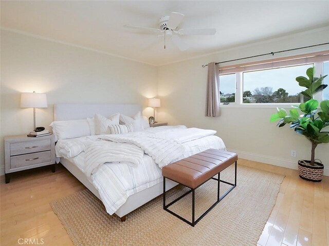 bedroom featuring wood finished floors, ceiling fan, baseboards, and multiple windows