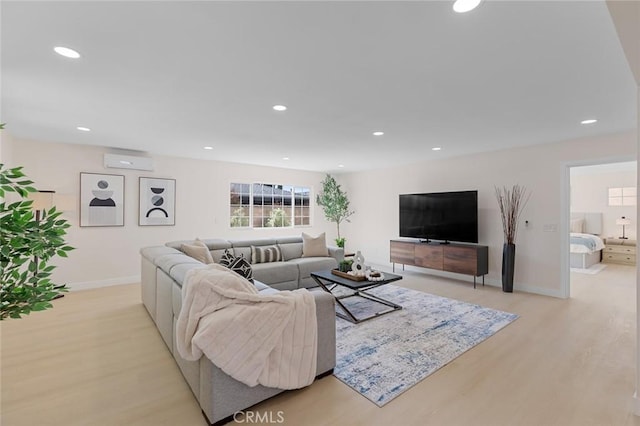 living area featuring baseboards, light wood-style flooring, recessed lighting, and a wall mounted air conditioner