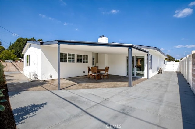 rear view of house featuring a fenced backyard, a patio, a chimney, and stucco siding