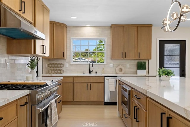 kitchen with an inviting chandelier, light wood-style floors, under cabinet range hood, a sink, and appliances with stainless steel finishes