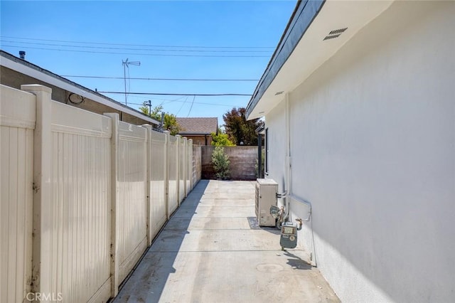 view of side of home with fence, stucco siding, and ac unit