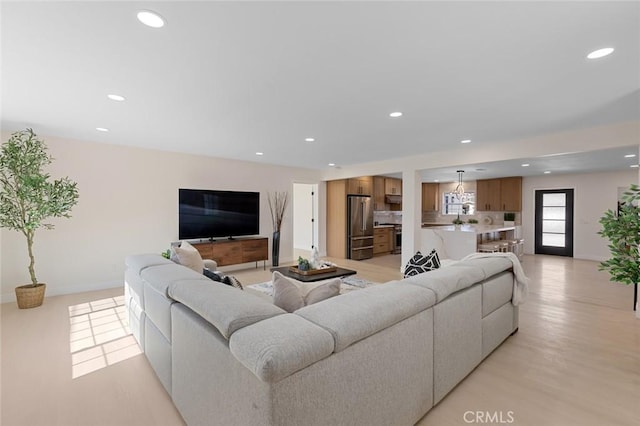 living area with recessed lighting, baseboards, and light wood-type flooring