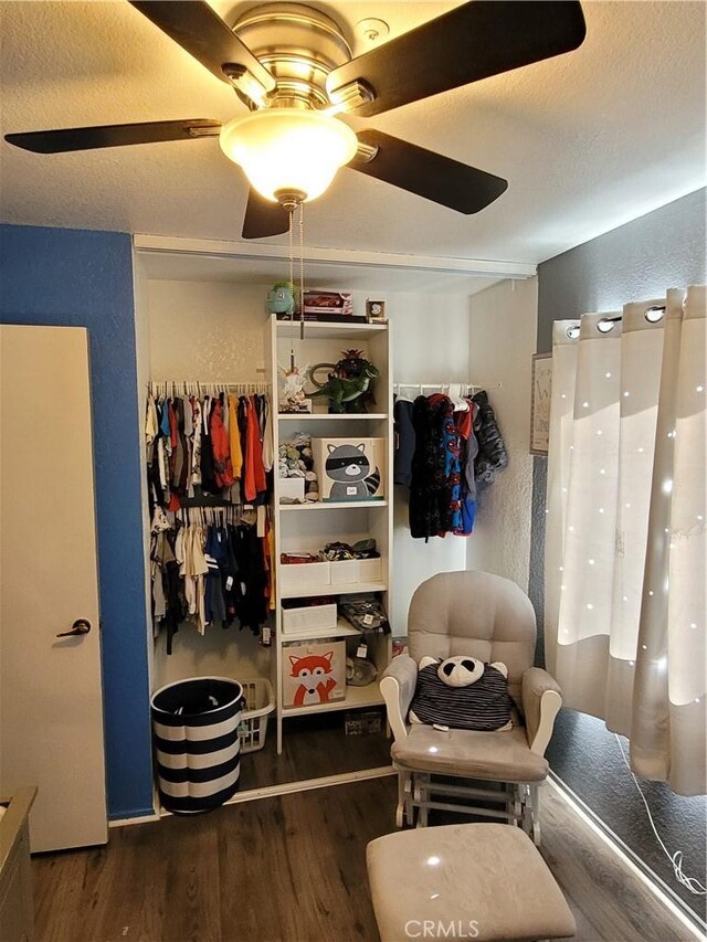 bedroom featuring wood finished floors, a ceiling fan, and a textured wall
