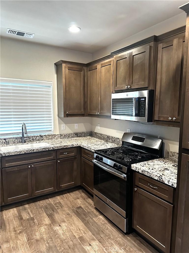 16 Petaluma Ct, Chico, CA 95926 - kitchen with appliances with stainless steel finishes, a sink, dark brown cabinets, wood finished floors, and light stone counters