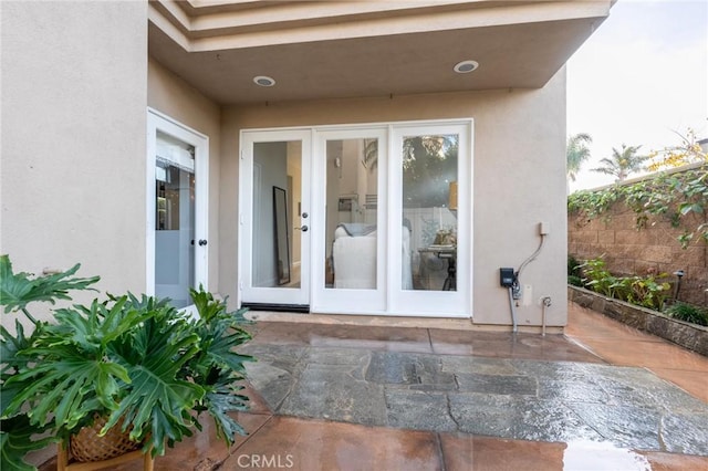entrance to property with stucco siding, french doors, and a patio