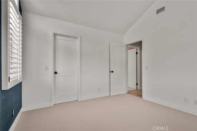 unfurnished bedroom featuring carpet flooring, multiple windows, lofted ceiling, and baseboards