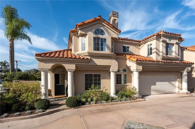 mediterranean / spanish house featuring concrete driveway, stucco siding, an attached garage, and a chimney