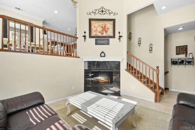 carpeted living room featuring visible vents, baseboards, recessed lighting, a premium fireplace, and stairs