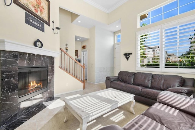living area with ornamental molding, a towering ceiling, a premium fireplace, and stairway