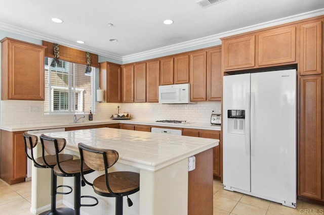 kitchen featuring light tile patterned floors, white appliances, backsplash, and a center island