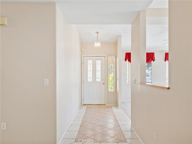 entrance foyer with baseboards, light tile patterned floors, and a chandelier