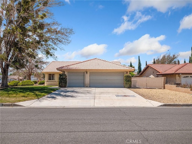 ranch-style home with a tiled roof, fence, concrete driveway, an attached garage, and stucco siding