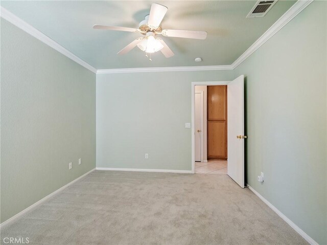 empty room with carpet flooring, a ceiling fan, baseboards, visible vents, and ornamental molding