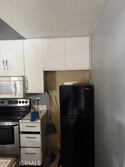 82 Largo St, Laguna Niguel, CA 92677 - kitchen featuring freestanding refrigerator, white microwave, stainless steel range with electric stovetop, white cabinetry, and a textured ceiling