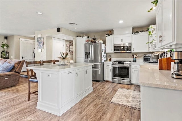 7440 Shale Rock Rd, Paso Robles, CA 93446 - kitchen featuring stainless steel appliances, a breakfast bar area, light wood-style flooring, white cabinetry, and a center island