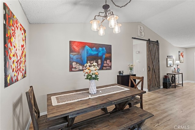 28646 Patti Ln, Menifee, CA 92585 - dining room featuring a barn door, lofted ceiling, light wood-style floors, a chandelier, and a textured ceiling