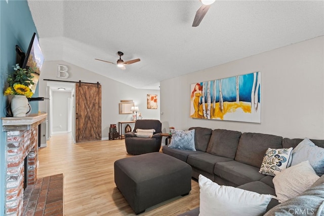 28646 Patti Ln, Menifee, CA 92585 - living room featuring ceiling fan, a barn door, light wood-type flooring, a textured ceiling, and vaulted ceiling