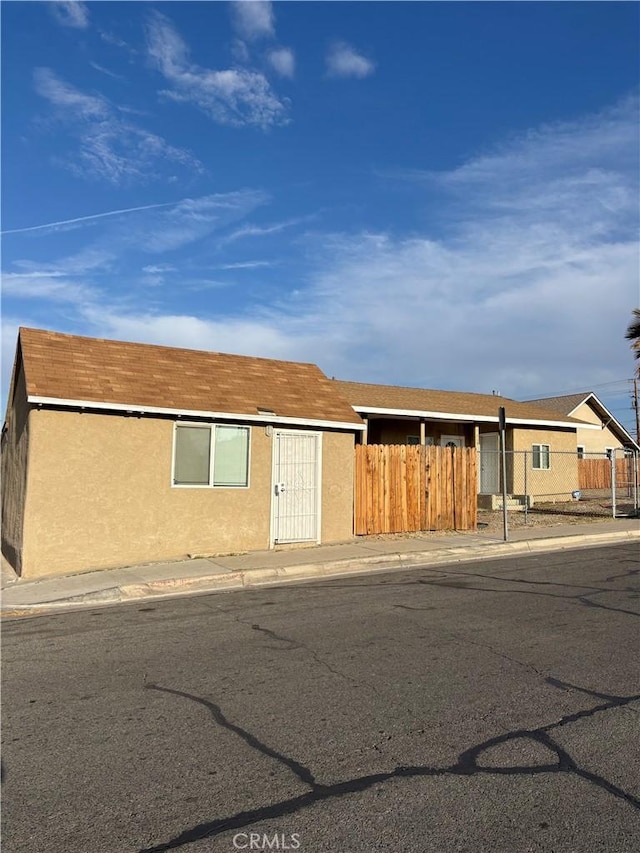view of front facade with fence and stucco siding