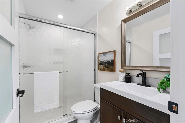 bathroom featuring toilet, a stall shower, recessed lighting, and vanity