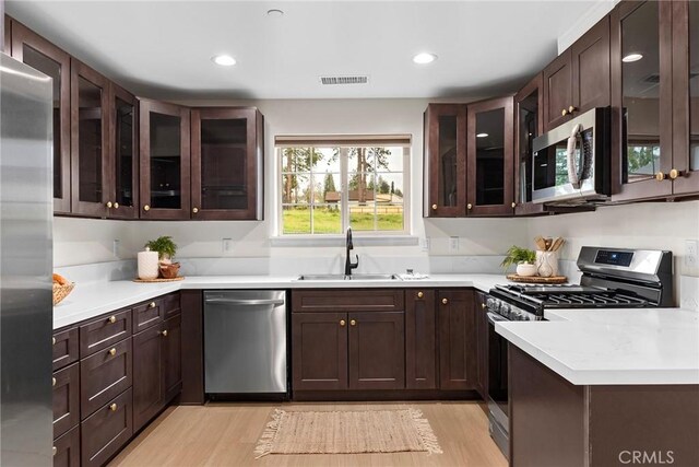 kitchen featuring a sink, appliances with stainless steel finishes, visible vents, light wood-style floors, and light countertops