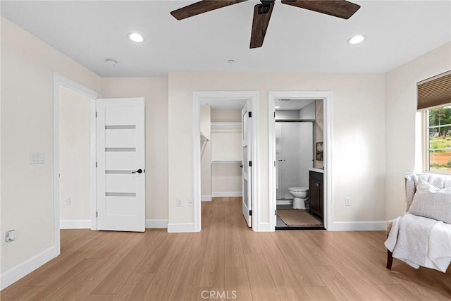 bedroom with a walk in closet, baseboards, light wood-style flooring, and recessed lighting