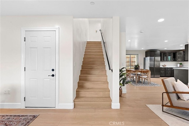 stairs with recessed lighting, wood finished floors, and baseboards