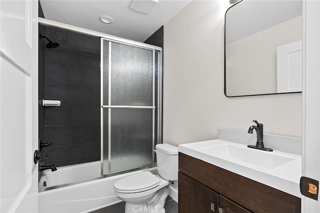 full bathroom featuring combined bath / shower with glass door, vanity, and toilet