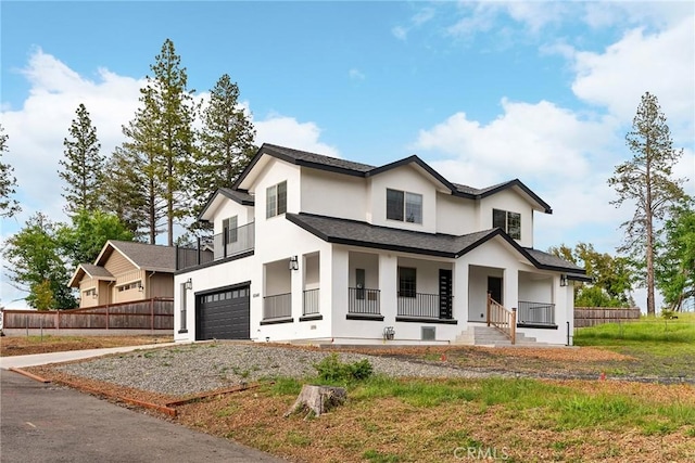 modern inspired farmhouse featuring a porch, gravel driveway, stucco siding, fence, and a garage