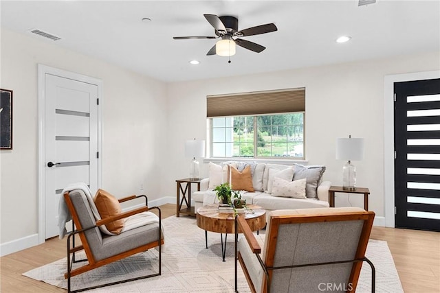 living area featuring baseboards, visible vents, ceiling fan, and light wood-style floors