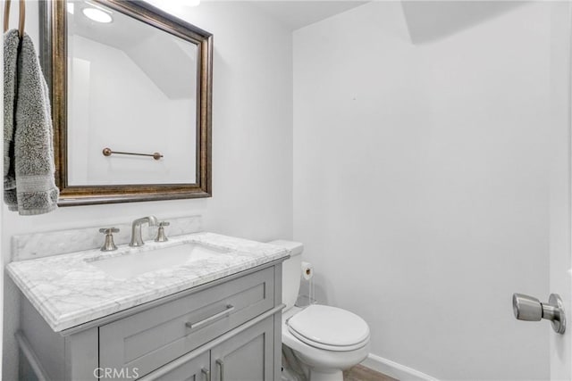 half bath with toilet, vanity, and baseboards
