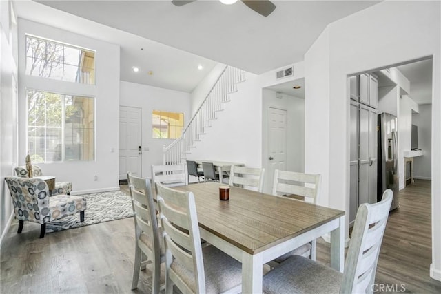 dining room featuring visible vents, wood finished floors, ceiling fan, and stairs