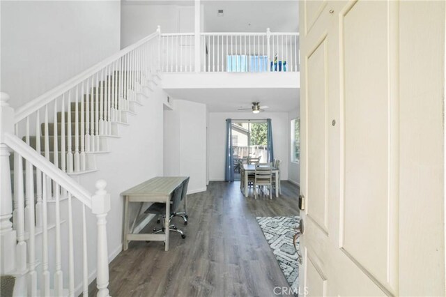 foyer entrance with a towering ceiling, a ceiling fan, stairway, and wood finished floors