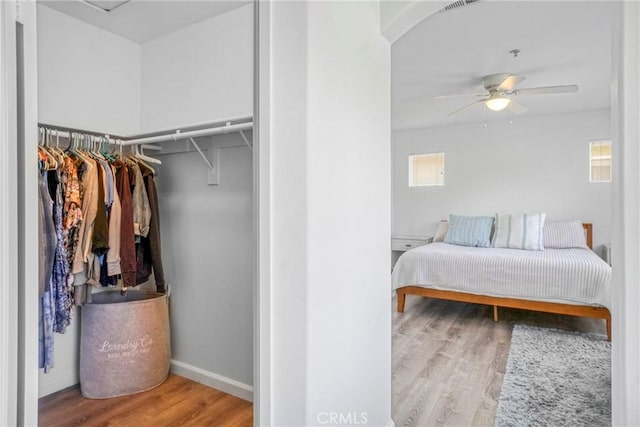 bedroom with multiple windows, ceiling fan, wood finished floors, and visible vents