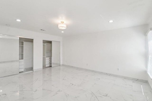 unfurnished bedroom with recessed lighting, multiple closets, marble finish floor, baseboards, and visible vents