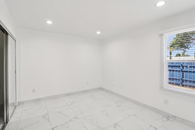 unfurnished room with recessed lighting, marble finish floor, and baseboards