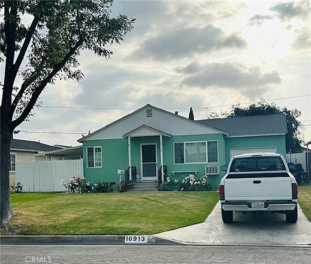view of front facade with fence, a wall mounted AC, concrete driveway, and a front lawn