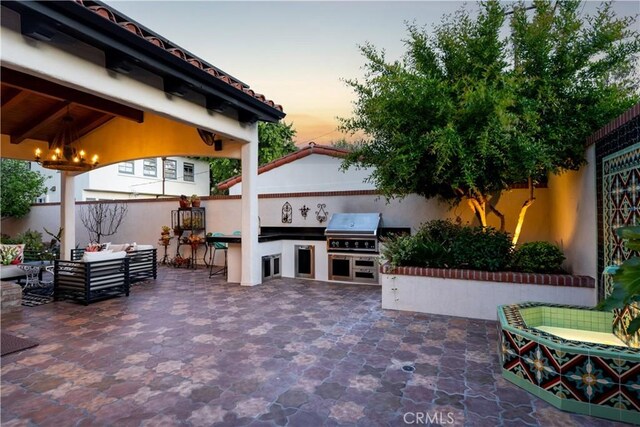 2020 N Victoria Dr, Santa Ana, CA 92706 - patio terrace at dusk featuring exterior kitchen, area for grilling, a fenced backyard, and an outdoor living space