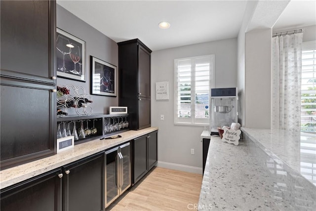 28934 Rangeview Dr, Murrieta, CA 92563 - kitchen with wine cooler, baseboards, light stone countertops, light wood-style floors, and recessed lighting