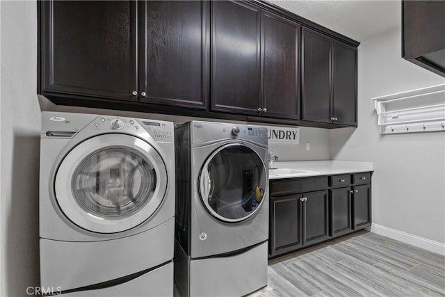 28934 Rangeview Dr, Murrieta, CA 92563 - laundry area featuring cabinet space, washer and dryer, baseboards, and light wood-style floors