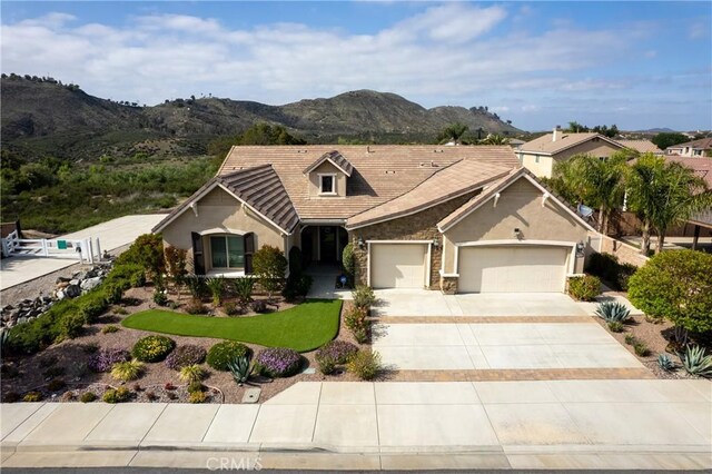 28934 Rangeview Dr, Murrieta, CA 92563 - view of front facade featuring stone siding, a garage, stucco siding, a mountain view, and driveway