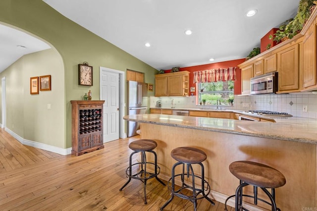 3161921 Via Puerta Del Sol, Bonsall, CA 92003 - kitchen with decorative backsplash, light wood-style flooring, appliances with stainless steel finishes, vaulted ceiling, and a peninsula