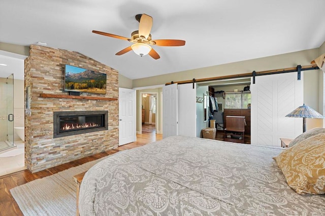 3161921 Via Puerta Del Sol, Bonsall, CA 92003 - bedroom with wood finished floors, a barn door, a fireplace, a ceiling fan, and lofted ceiling