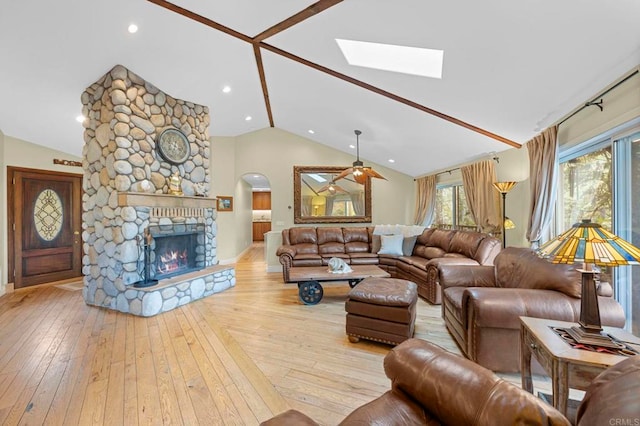 3161921 Via Puerta Del Sol, Bonsall, CA 92003 - living room with vaulted ceiling with skylight, a fireplace, ceiling fan, baseboards, and hardwood / wood-style flooring