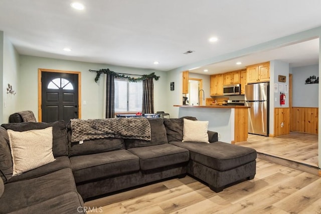 living room with visible vents, light wood-type flooring, recessed lighting, and a wainscoted wall