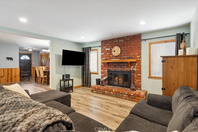 living room with recessed lighting, wood finished floors, and a brick fireplace